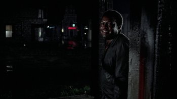 Movie still from “Uptight” (1968), directed by Jules Dassin – A man standing next to a building at night; Medium shot, Low angle