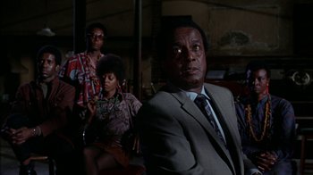 Movie still from “Uptight” (1968), directed by Jules Dassin – A man in a suit and tie next to a woman in a dress; Medium shot, Low angle