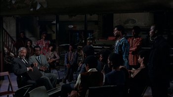 Movie still from “Uptight” (1968), directed by Jules Dassin – A group of people sitting in a room; Wide shot, High angle