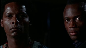 Movie still from “Uptight” (1968), directed by Jules Dassin – Two men are standing in the dark looking at each other; Close Up shot, Low angle