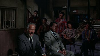 Movie still from “Uptight” (1968), directed by Jules Dassin – A group of men and women sitting in a room together; Medium shot, High angle
