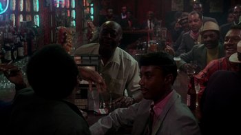 Movie still from “Uptight” (1968), directed by Jules Dassin – A group of people sitting at a table in a bar; Medium shot, Over the shoulder angle