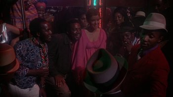 Movie still from “Uptight” (1968), directed by Jules Dassin – A group of people standing around in a room; Medium shot, High angle