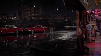 Movie still from “Uptight” (1968), directed by Jules Dassin – A man walking in the rain next to a red car; Extreme Wide shot, High angle