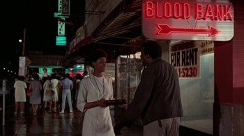 Movie still from “Uptight” (1968), directed by Jules Dassin – A man and a woman standing in front of a store; Medium shot, Over the shoulder angle