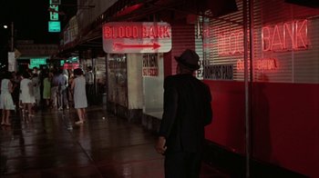 Movie still from “Uptight” (1968), directed by Jules Dassin – A man wearing a hat standing in front of a store; Wide shot, High angle
