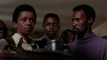 Movie still from “Uptight” (1968), directed by Jules Dassin – A group of people standing around a table; Medium shot, Low angle