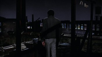 Movie still from “Uptight” (1968), directed by Jules Dassin – A man standing on a roof at night; Wide shot, High angle