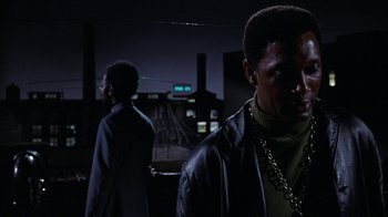 Movie still from “Uptight” (1968), directed by Jules Dassin – Two men standing next to each other in a dark room; Medium shot, Low angle