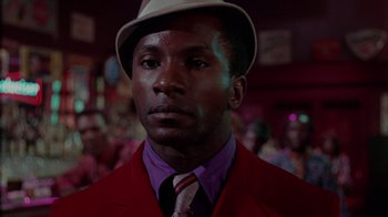 Movie still from “Uptight” (1968), directed by Jules Dassin – A person wearing a suit and a hat; Close Up shot, Low angle