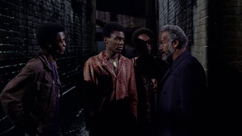Movie still from “Uptight” (1968), directed by Jules Dassin – A group of men standing next to each other in an alleyway; Medium shot, High angle