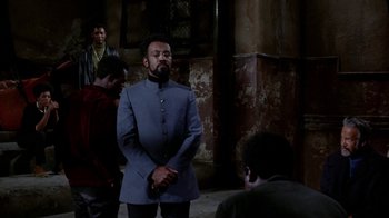 Movie still from “Uptight” (1968), directed by Jules Dassin – A man in a blue suit standing in front of other men; Medium shot, Over the shoulder angle