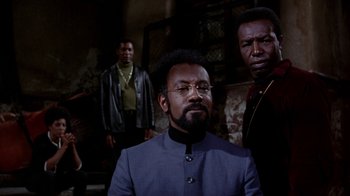 Movie still from “Uptight” (1968), directed by Jules Dassin – A group of men standing next to each other in a room; Medium shot, Low angle