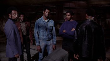 Movie still from “Uptight” (1968), directed by Jules Dassin – A group of men standing next to each other in a room; Medium shot, High angle