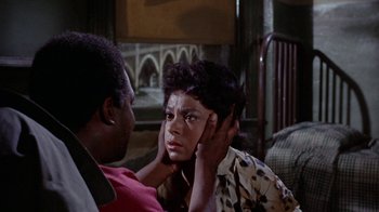 Movie still from “Uptight” (1968), directed by Jules Dassin – An african - american woman holding her hands to her ear; Medium shot, Over the shoulder angle