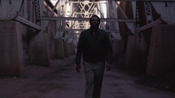 Movie still from “Uptight” (1968), directed by Jules Dassin – A man is walking in the dark under a bridge; Wide shot, Low angle