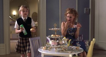 Movie still from “Uptown Girls” (2003), directed by Boaz Yakin – A woman sitting at a table in front of a child; Medium shot, Over the shoulder angle
