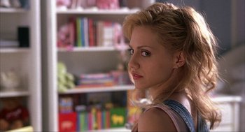 Movie still from “Uptown Girls” (2003), directed by Boaz Yakin – A woman is looking into the distance in front of a book shelf; Close Up shot, Over the shoulder angle