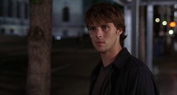 Movie still from “Uptown Girls” (2003), directed by Boaz Yakin – A young man standing in front of a tree at night; Close Up shot, Over the shoulder angle