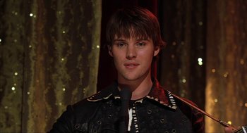 Movie still from “Uptown Girls” (2003), directed by Boaz Yakin – A man with a microphone in front of a microphone stand; Close Up shot, Over the shoulder angle