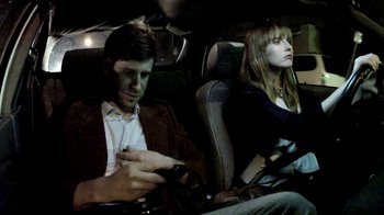 Movie still from “V/H/S/2” (2013), directed by Timo Tjahjanto – A man and a woman sitting in the back of a car; Medium shot, Overhead angle