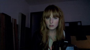 Movie still from “V/H/S/2” (2013), directed by Timo Tjahjanto – A woman with long red hair is taking a picture; Close Up shot, Low angle