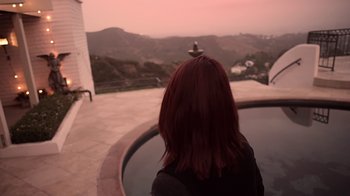 Movie still from “V/H/S/2” (2013), directed by Timo Tjahjanto – A woman with red hair standing in front of a fountain; Medium shot, High angle