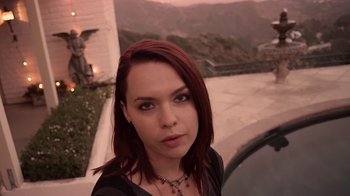 Movie still from “V/H/S/2” (2013), directed by Timo Tjahjanto – A beautiful woman with red hair standing next to a building; Close Up shot, Low angle