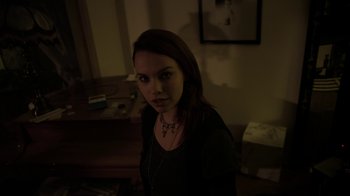 Movie still from “V/H/S/2” (2013), directed by Timo Tjahjanto – A woman in a black shirt is in a dark room; Medium shot, Over the shoulder angle