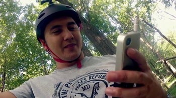 Movie still from “V/H/S/2” (2013), directed by Timo Tjahjanto – A man wearing a bicycle helmet while looking at his cell phone; Close Up shot, Low angle