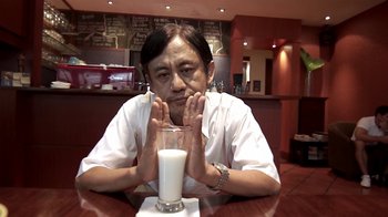 Movie still from “V/H/S/2” (2013), directed by Timo Tjahjanto – A man sitting in front of a glass of milk; Close Up shot, High angle