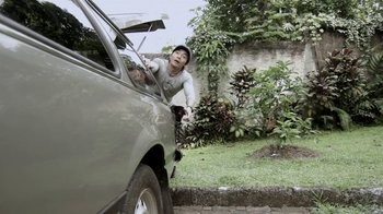 Movie still from “V/H/S/2” (2013), directed by Timo Tjahjanto – A man in a white shirt is leaning on a silver car; Medium shot, Low angle