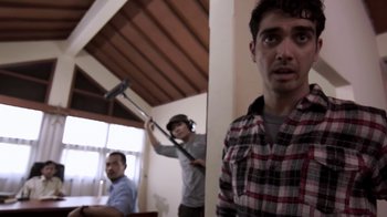 Movie still from “V/H/S/2” (2013), directed by Timo Tjahjanto – Two men are playing a video game in a living room; Medium shot, Over the shoulder angle