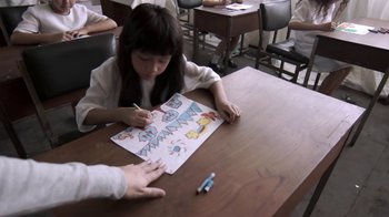 Movie still from “V/H/S/2” (2013), directed by Timo Tjahjanto – A young girl is drawing a picture on a table; Close Up shot, High angle