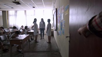 Movie still from “V/H/S/2” (2013), directed by Timo Tjahjanto – A group of people standing in a room; Wide shot, Over the shoulder angle