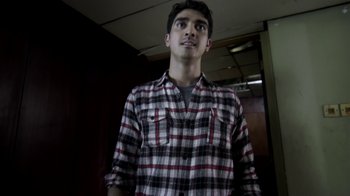 Movie still from “V/H/S/2” (2013), directed by Timo Tjahjanto – A man in a plaid shirt looking up at the ceiling; Medium shot, Low angle