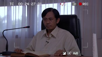Movie still from “V/H/S/2” (2013), directed by Timo Tjahjanto – A man sitting at a desk with a book in front of him; Close Up shot, Over the shoulder angle