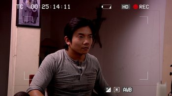 Movie still from “V/H/S/2” (2013), directed by Timo Tjahjanto – A man sitting in front of a camera; Medium shot, Over the shoulder angle