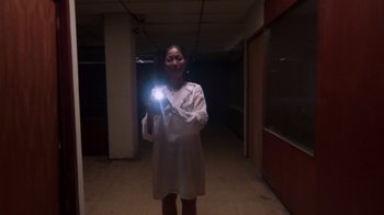 Movie still from “V/H/S/2” (2013), directed by Timo Tjahjanto – A woman holding a flashlight in a dark room; Medium shot, Low angle