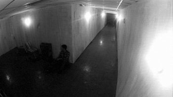 Movie still from “V/H/S/2” (2013), directed by Timo Tjahjanto – A person is sitting in a dark hallway; Extreme Wide shot, High angle