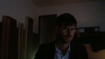 Movie still from “V/H/S/2” (2013), directed by Timo Tjahjanto – A man in a suit is looking at the camera; Close Up shot, High angle