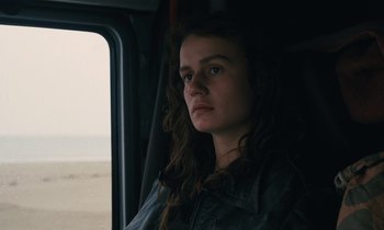 Movie still from “Vagabond” (1985), directed by Agnès Varda – A woman sitting in a vehicle looking out the window; Close Up shot, Over the shoulder angle