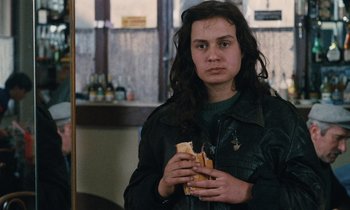 Movie still from “Vagabond” (1985), directed by Agnès Varda – A woman holding a sandwich in her hands; Close Up shot, Over the shoulder angle