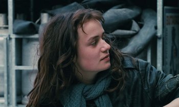 Movie still from “Vagabond” (1985), directed by Agnès Varda – A person with long hair wearing a scarf; Close Up shot, Over the shoulder angle