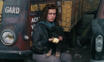 Movie still from “Vagabond” (1985), directed by Agnès Varda – A woman holding a dog and a banana; Medium shot, High angle