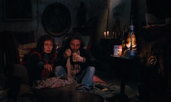 Movie still from “Vagabond” (1985), directed by Agnès Varda – A man and a woman sitting on the ground eating food; Medium shot, High angle
