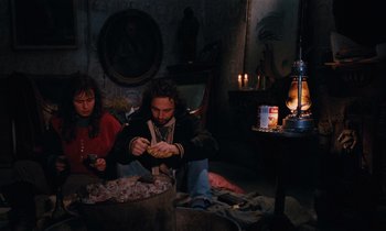Movie still from “Vagabond” (1985), directed by Agnès Varda – A man and a woman sitting on the floor in front of candles; Medium shot, High angle