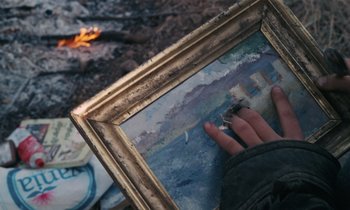 Movie still from “Vagabond” (1985), directed by Agnès Varda – A person holding a painting in front of a fire pit; Extreme Close Up shot, High angle