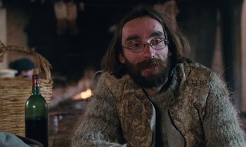 Movie still from “Vagabond” (1985), directed by Agnès Varda – A man with long hair and a beard wearing glasses; Close Up shot, Over the shoulder angle