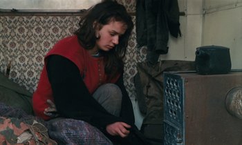 Movie still from “Vagabond” (1985), directed by Agnès Varda – A woman sitting on the ground looking at a computer; Medium shot, High angle